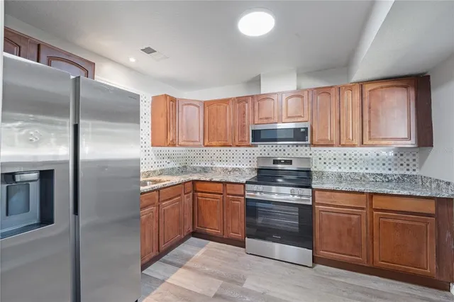 a kitchen with stainless steel appliances granite countertop a refrigerator and a stove top oven