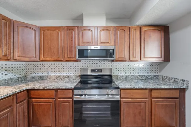 a kitchen with granite countertop white cabinets and stainless steel appliances