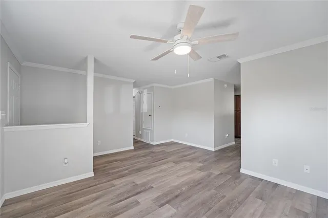 an empty room with wooden floor and fan