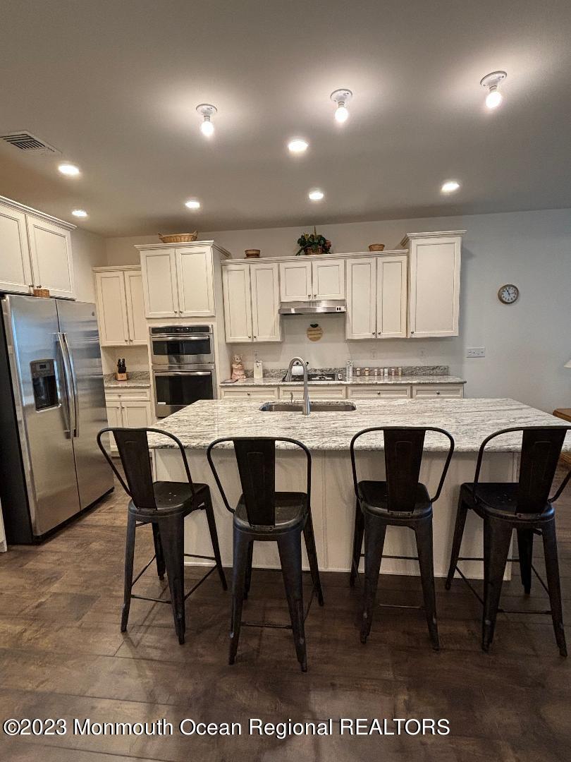 12 Harvest Ridge Road Howell, NJ 07731 - Photo 7 of 27 a kitchen with stainless steel appliances kitchen island granite countertop a table chairs sink and cabinets