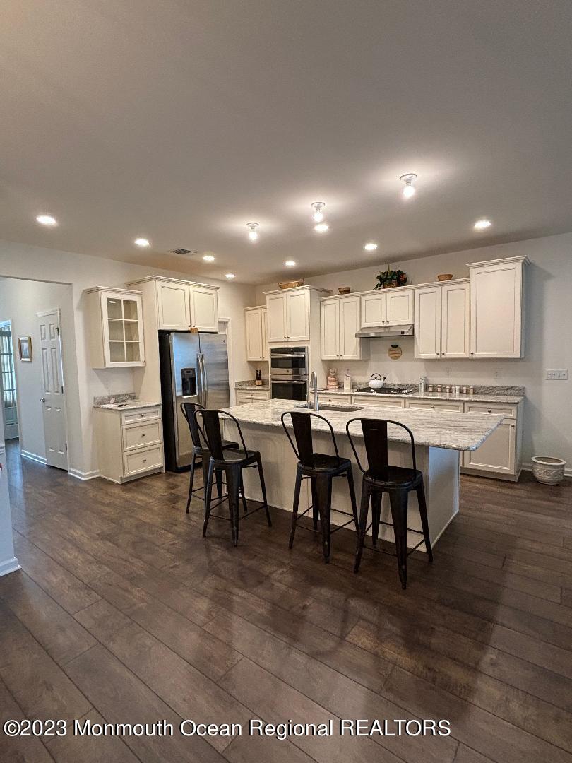 12 Harvest Ridge Road Howell, NJ 07731 - Photo 10 of 27 a kitchen with stainless steel appliances kitchen island granite countertop a table chairs sink and cabinets