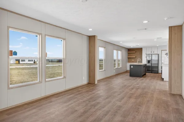 an empty room with kitchen and windows