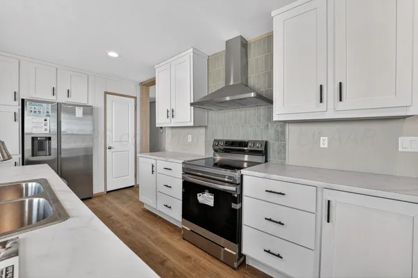 a kitchen with stainless steel appliances granite countertop a stove a refrigerator and a white cabinets