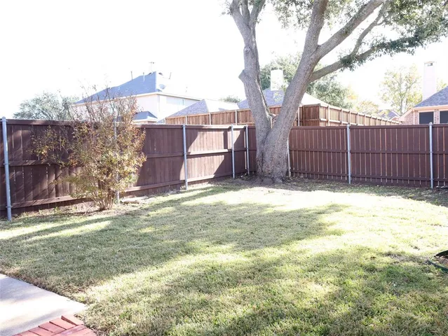 a view of a backyard with wooden fence and a large tree