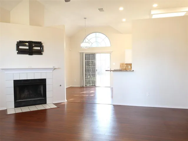 an empty room with wooden floor fireplace and windows