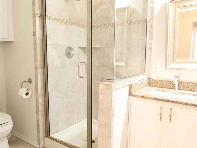 a bathroom with a granite countertop sink a toilet and shower