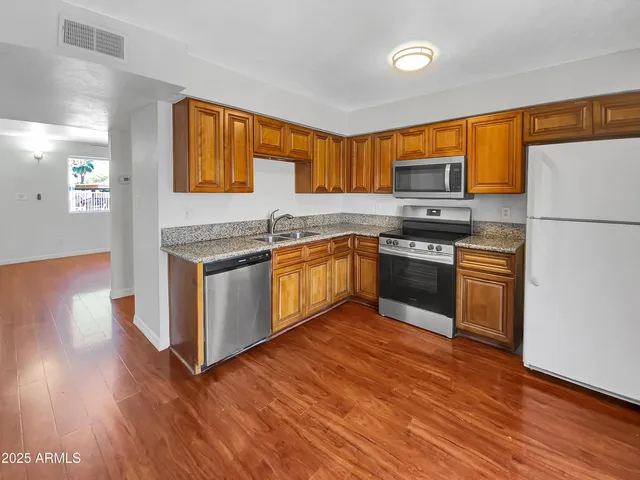 a kitchen with stainless steel appliances granite countertop a stove top oven a sink dishwasher and a refrigerator
