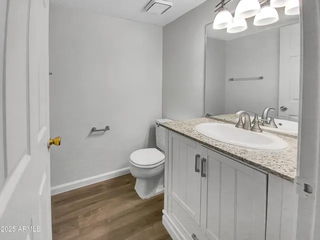 a bathroom with a granite countertop sink a toilet and a mirror