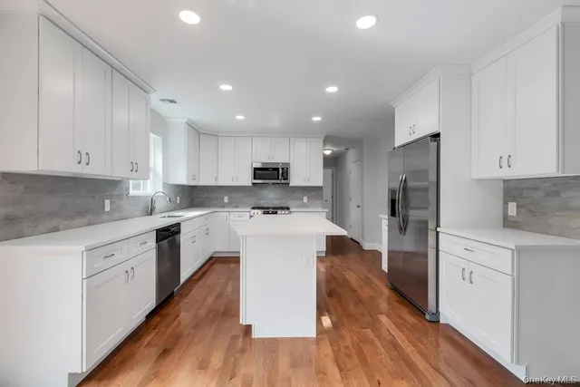 a kitchen with stainless steel appliances white cabinets sink and wooden floor