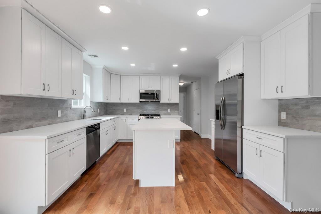 113 Currans Road Middle Island, NY 11953 - Photo 17 of 32 a kitchen with stainless steel appliances white cabinets sink and wooden floor