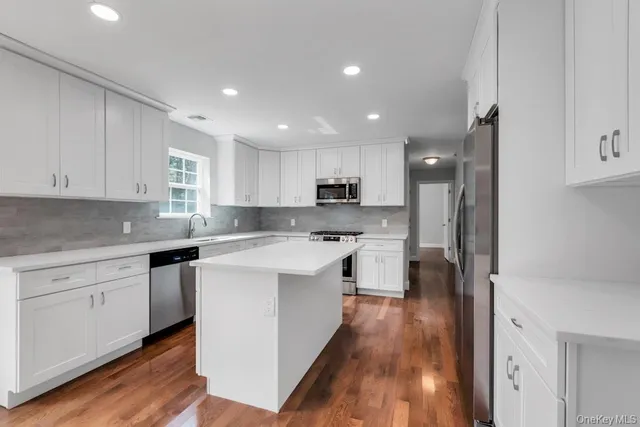 a kitchen with stainless steel appliances white cabinets sink and wooden floor