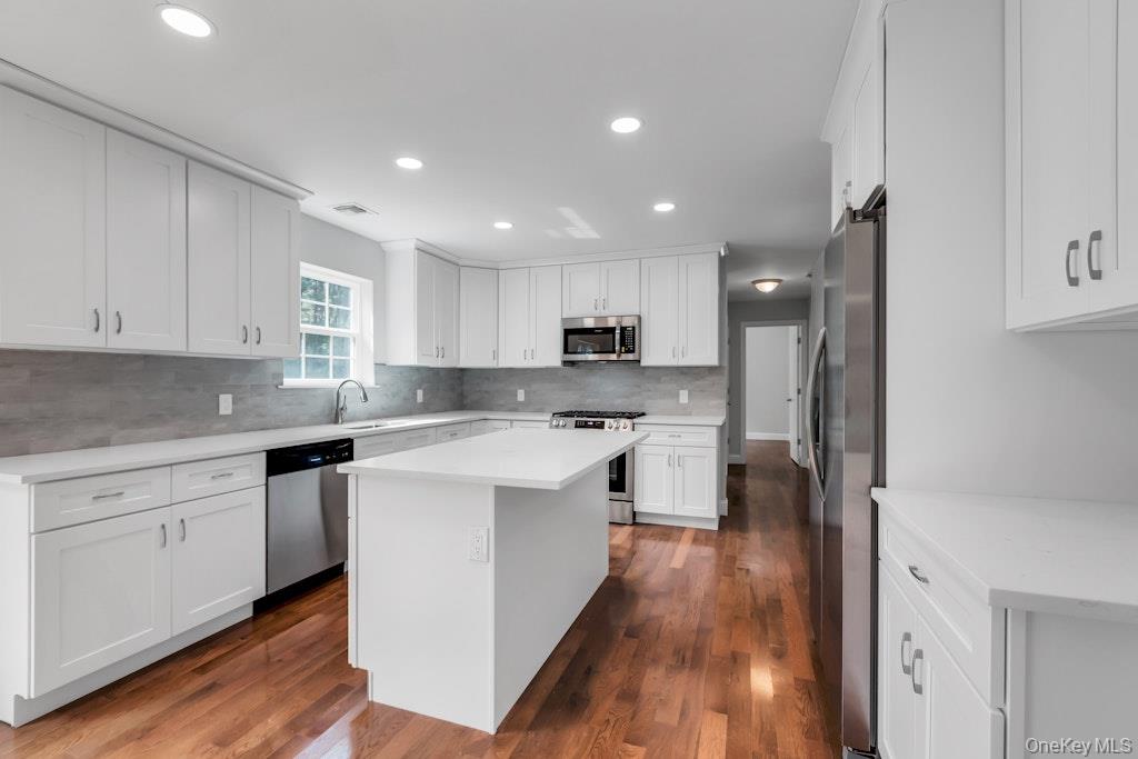 113 Currans Road Middle Island, NY 11953 - Photo 18 of 32 a kitchen with stainless steel appliances white cabinets sink and wooden floor
