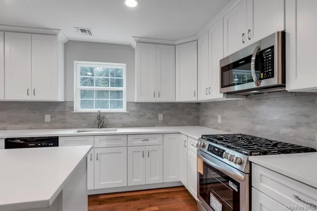 a kitchen with white cabinets and appliances