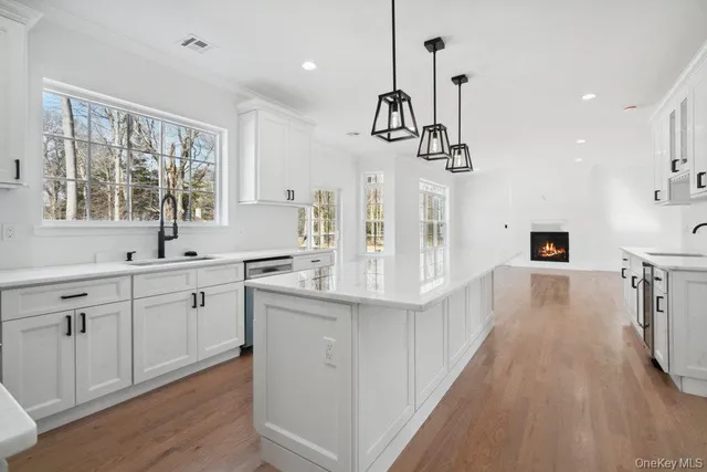 a very nice looking room with a large window wooden floor and stainless steel appliances