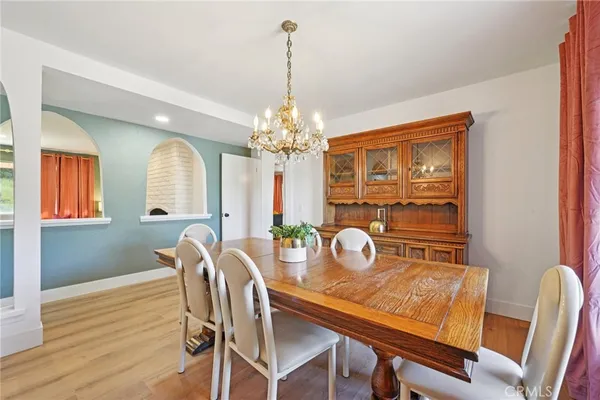 a kitchen with stainless steel appliances granite countertop a stove top oven a refrigerator and a dining table with wooden floor