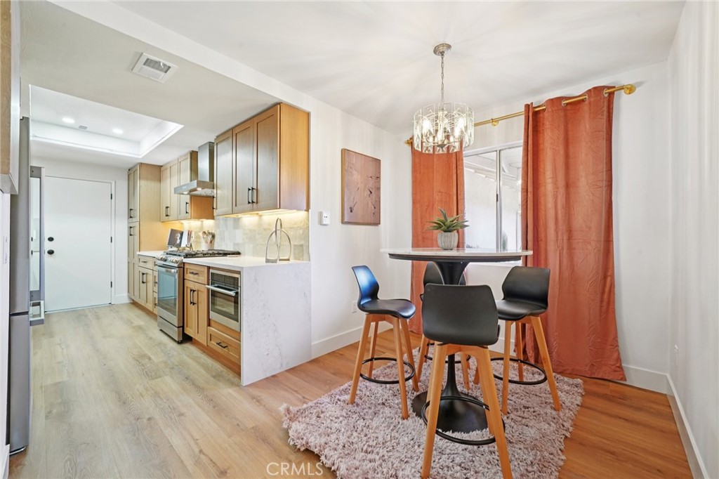 1500 Country Club Drive Riverside, CA 92506 - Photo 14 of 39 a kitchen with stainless steel appliances granite countertop a stove top oven a refrigerator and a dining table with wooden floor