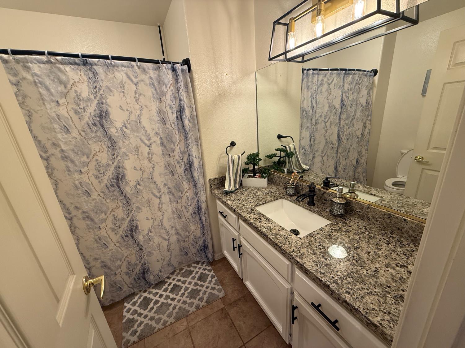 3124 Summer Lane Madera, CA 93637 - Photo 13 of 30 a bathroom with a granite countertop sink a mirror and shower