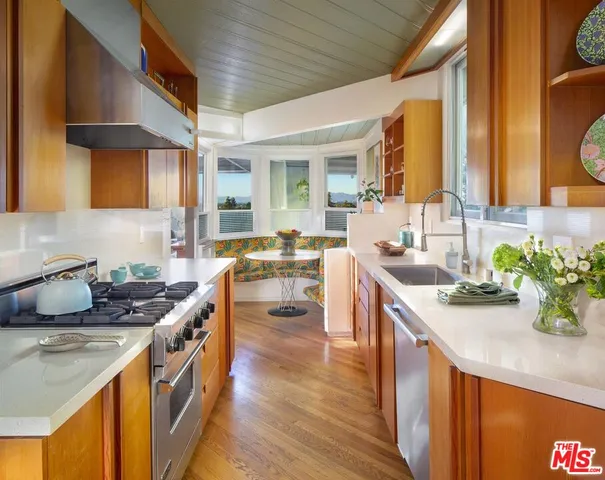 a kitchen with stainless steel appliances granite countertop a sink a stove and a wooden cabinets