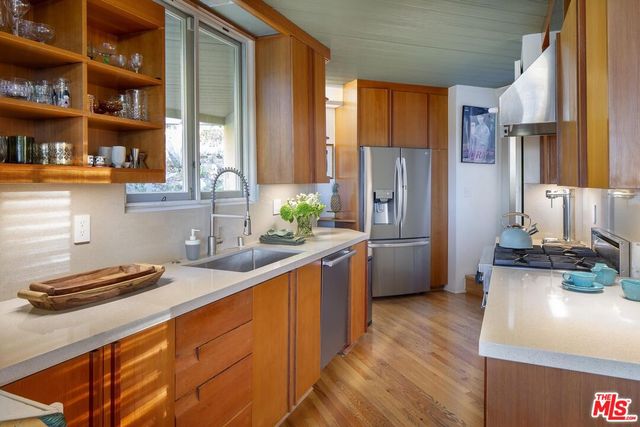 a kitchen with stainless steel appliances granite countertop a refrigerator a stove and a sink