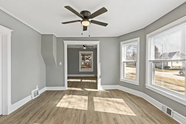 an empty room with wooden floor and windows