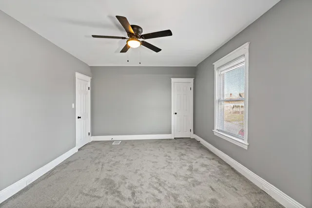 an empty room with wooden floor ceiling fan and windows