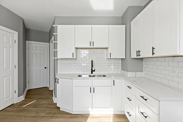 a kitchen with white cabinets sink and stove