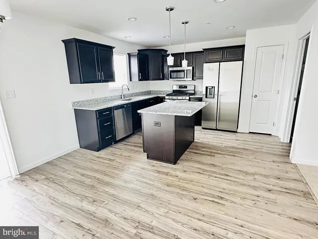 a kitchen with stainless steel appliances kitchen island granite countertop a refrigerator stove top oven and sink