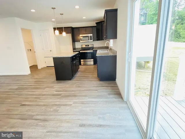 a view of kitchen with stainless steel appliances wooden floor and window