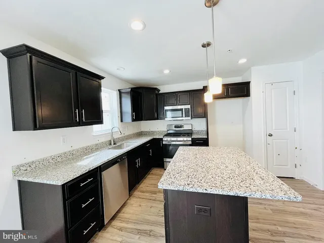 a kitchen with stainless steel appliances kitchen island granite countertop a sink stove and refrigerator