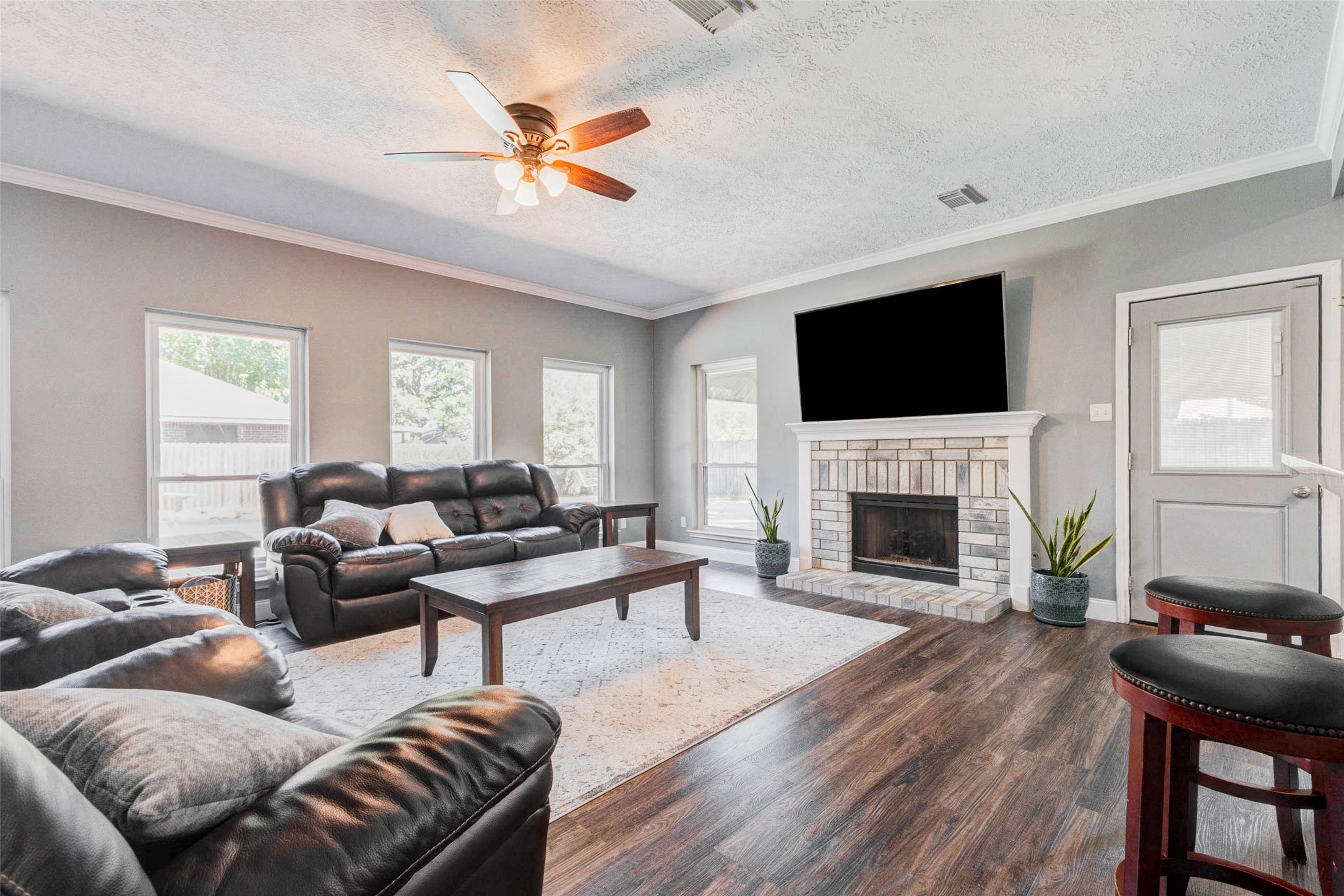 9215 Landry Boulevard Spring, TX 77379 - Photo 17 of 42 The spacious living area features wood look flooring, crown molding, abundant natural light, and a charming fireplace with a brick surround and custom mantle that serves as a beautiful focal point. Convenient backyard access is located just off the living room and kitchen.