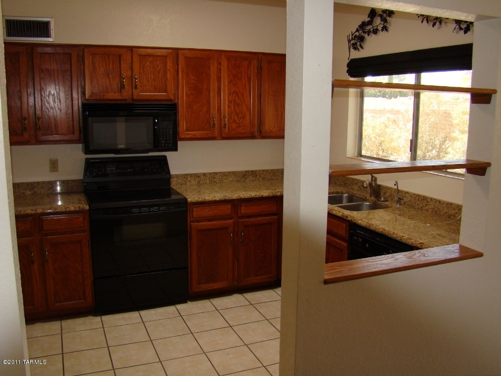 1443 North Rio-Aros Green Valley, AZ 85614 - Photo 6 of 19 a kitchen with granite countertop wooden cabinets and a stove top oven
