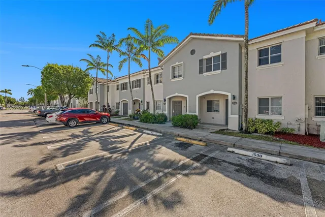 a front view of a house with a yard and parking