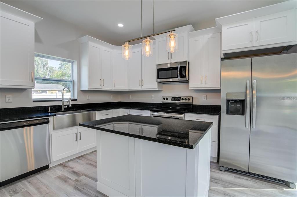 5630 Queener Avenue Port Richey, FL 34668 - Photo 15 of 37 a kitchen with granite countertop a refrigerator sink and microwave