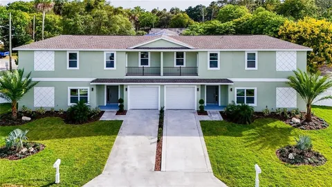 a front view of a house with a yard and potted plants