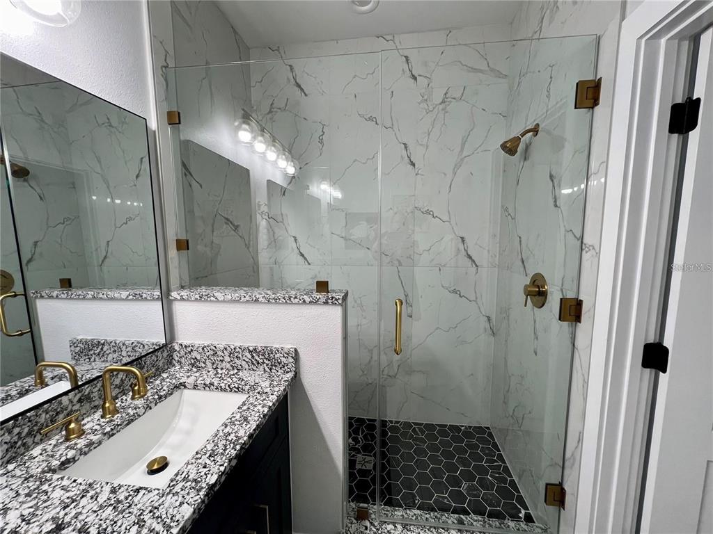 5630 Queener Avenue Port Richey, FL 34668 - Photo 29 of 37 a bathroom with a granite countertop sink a toilet and shower