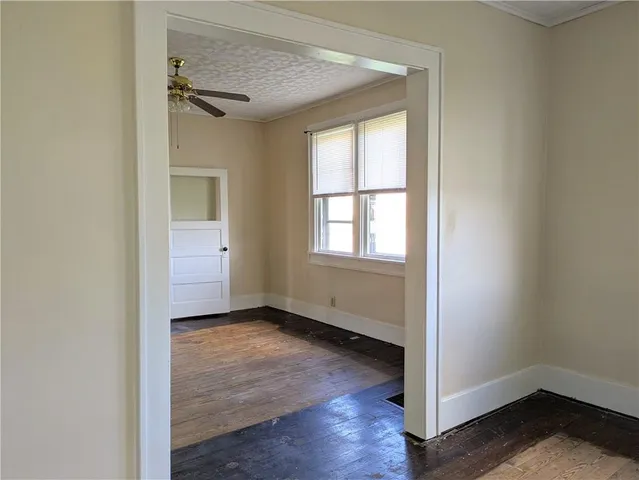 a view of an empty room with a window and wooden floor