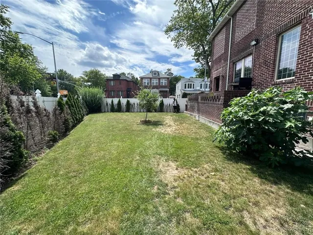 a view of a backyard with plants and large trees