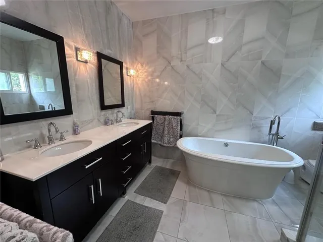 a spacious bathroom with a double vanity sink mirror and bathtub