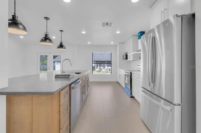 a kitchen with stainless steel appliances granite countertop a refrigerator a sink dishwasher a stove and a sink with wooden floor