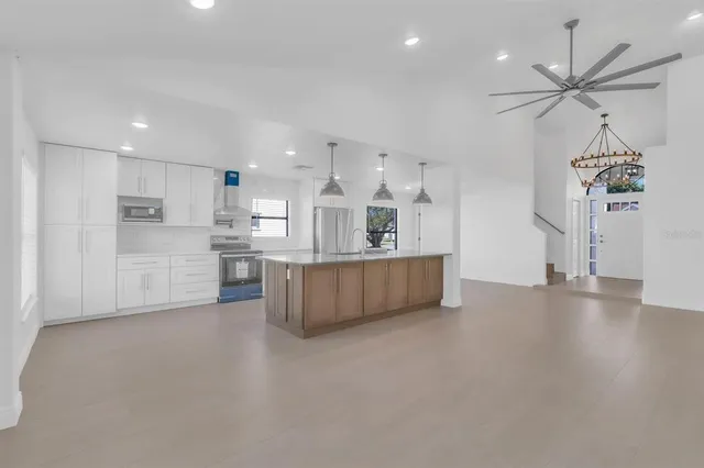 a view of kitchen with kitchen island white cabinets and stainless steel appliances