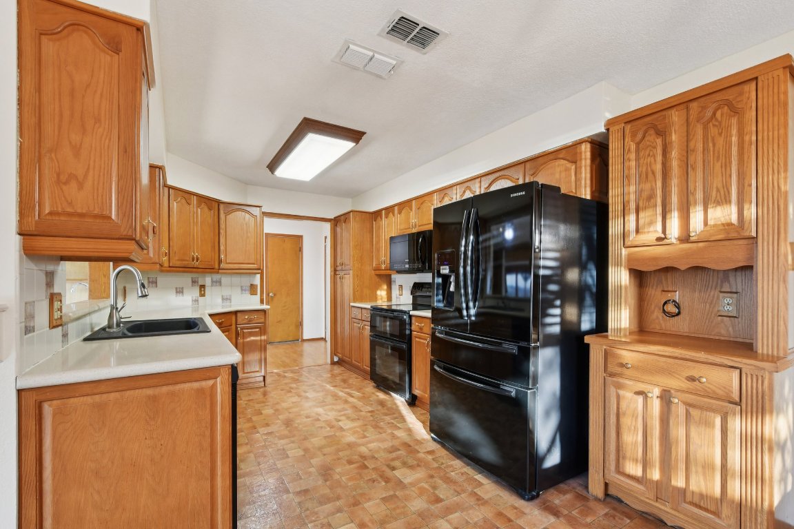 21009 Fawn Ridge Drive Lago Vista, TX 78645 - Photo 12 of 40 a kitchen with stainless steel appliances granite countertop a stove top oven a sink a refrigerator and white cabinets with wooden floor