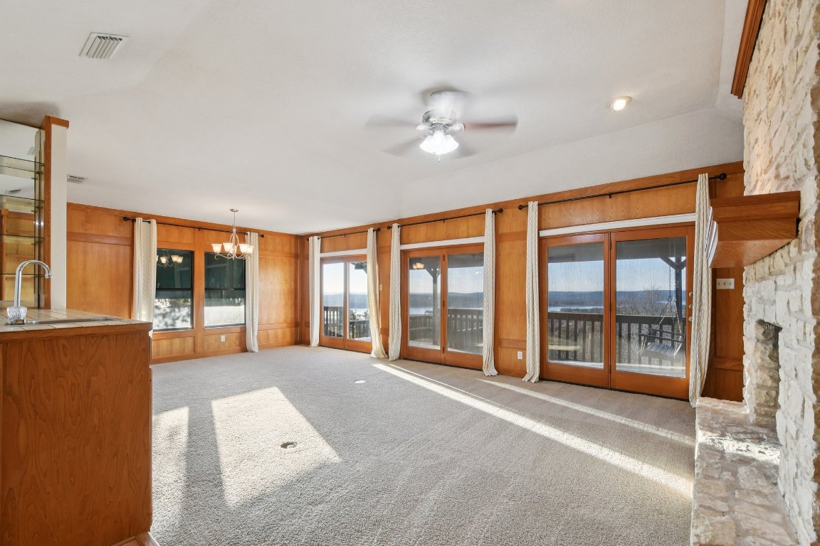 21009 Fawn Ridge Drive Lago Vista, TX 78645 - Photo 9 of 40 Unfurnished living room with a ceiling fan, light carpet, lofted ceiling, and a chandelier