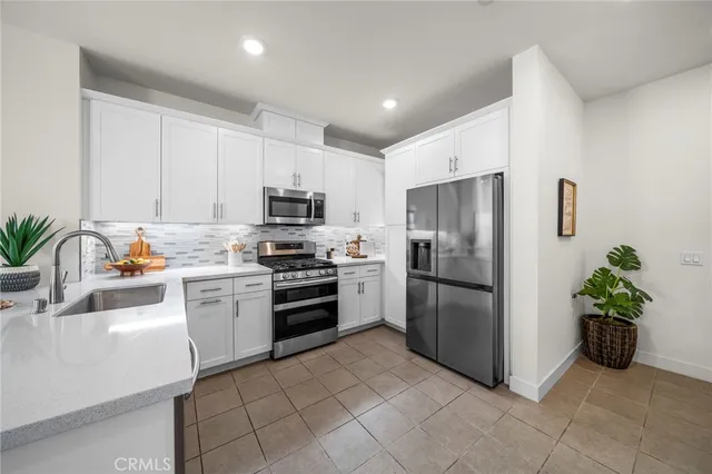 a kitchen with a refrigerator a microwave a sink a stove and white cabinets
