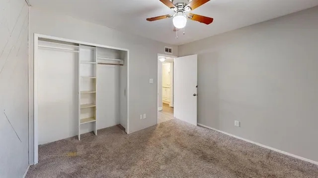 an empty room with a chandelier fan and closet