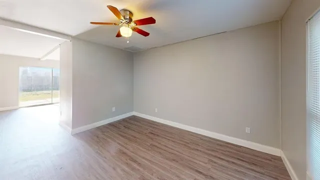 a view of an empty room and window with a fan
