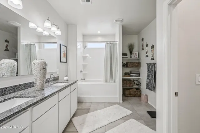 a bathroom with a granite countertop double vanity sink a mirror and a bathtub