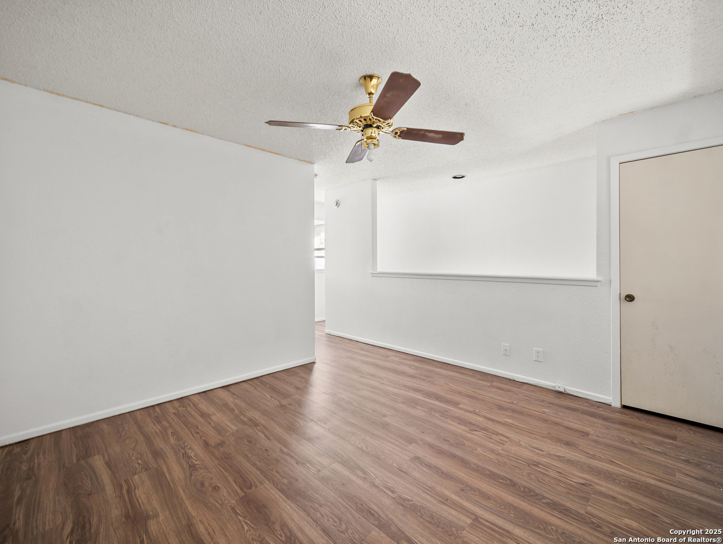 11520 Huebner Road, Unit 302 San Antonio, TX 78230 - Photo 19 of 28 an empty room with wooden floor ceiling fan and windows