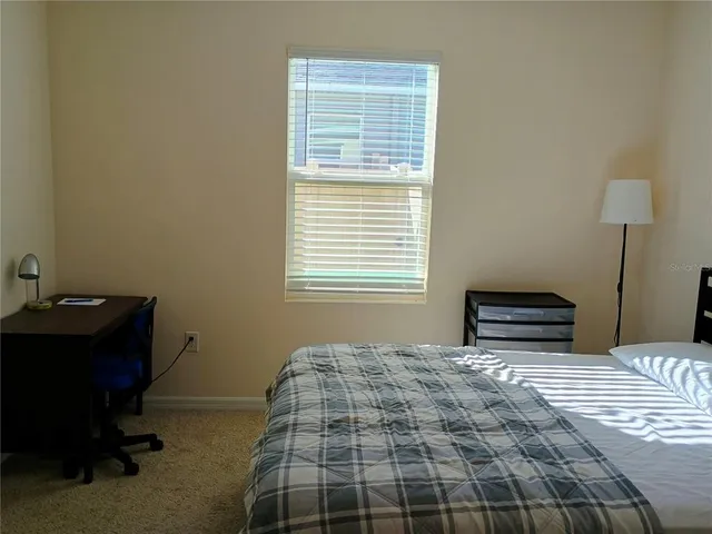 a bedroom with a bed and a computer on a table