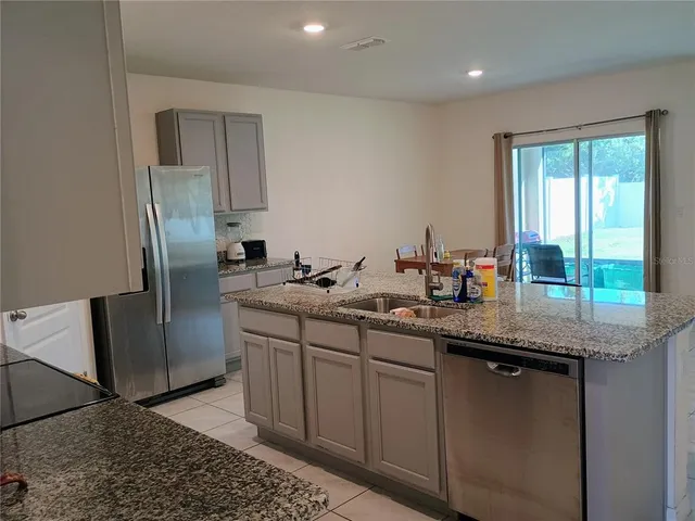 a kitchen with stainless steel appliances granite countertop a sink and a refrigerator