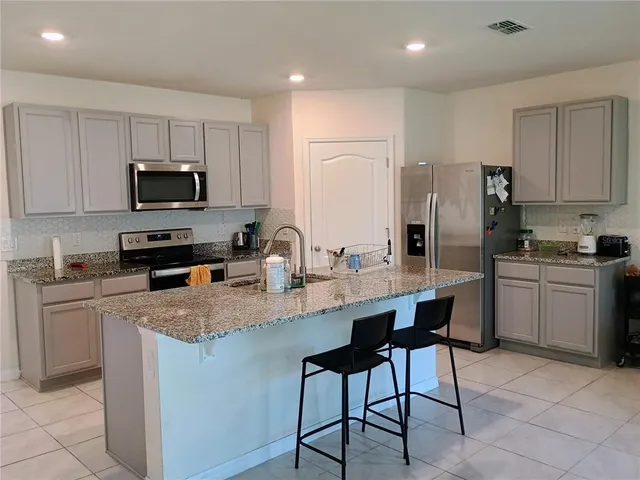 a kitchen with stainless steel appliances granite countertop a stove a sink a microwave a window and white cabinets